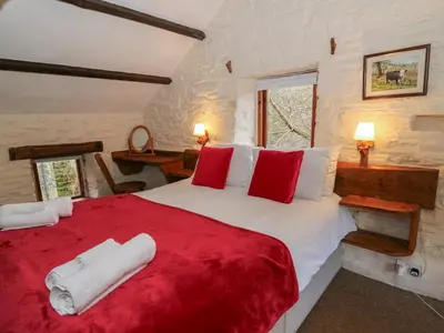a bedroom with a large bed with red and white pillows at Ty Tarw in Llanybydder