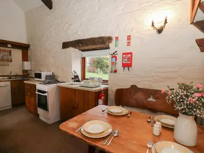 a kitchen with a wooden table and a stove at Ty Tarw in Llanybydder