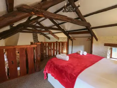 a bedroom with a large bed with a red blanket at Ty Tarw in Llanybydder