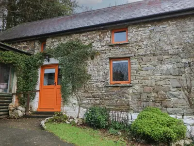 an old stone house with an orange door at Ty Ceffylau in Llanybydder