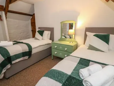 a bedroom with two beds and a mirror at Ty Ceffylau in Llanybydder