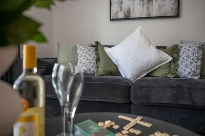 a living room with a couch and a table with a wine glass at Barmouth High Street Family Apartment in Barmouth