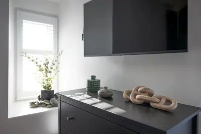 a room with a black dresser with a television on the wall at Barmouth High Street Family Apartment in Barmouth