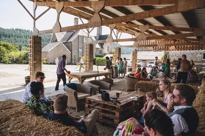 a group of people sitting in hay under a pavilion at Wilde Lodge by Birch Stays in Bucknell