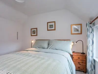 a bedroom with a bed and a dresser and a window at Gwelfor in Harlech