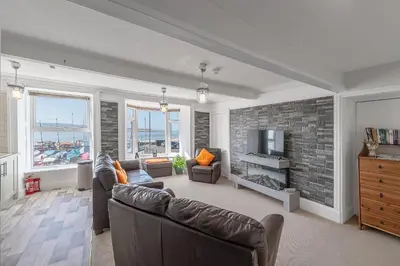 a living room with two couches and a tv at Spacious 3 Bedroom Sea View Flat in Aberdyfi