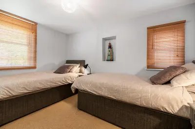 two beds in a bedroom with two windows at Spacious 3 Bedroom Sea View Flat in Aberdyfi