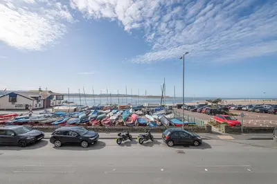 a parking lot with cars and boats in a harbor at Spacious 3 Bedroom Sea View Flat in Aberdyfi