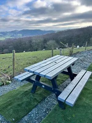 a picnic table in a field with sheep in the background at Carol Anns Caravan, Working Farm Stay, Rural, Private, Fire Pit for hire, Dogs on request in Pontesbury