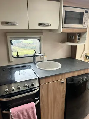 a kitchen with a stove and a sink and a microwave at Carol Anns Caravan, Working Farm Stay, Rural, Private, Fire Pit for hire, Dogs on request in Pontesbury