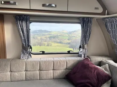 a couch in the back of a van with a window at Carol Anns Caravan, Working Farm Stay, Rural, Private, Fire Pit for hire, Dogs on request in Pontesbury