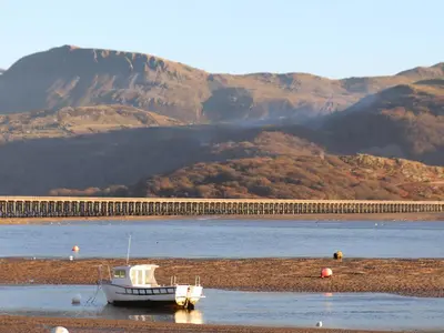a boat sitting on the shore of a body of water at Sandcastles in Barmouth