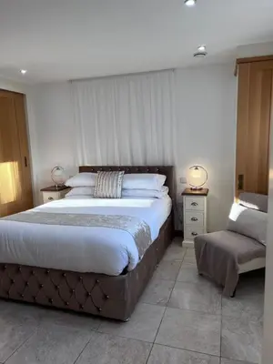 a bedroom with a large bed and a chair at Falconwood in Ifton Heath