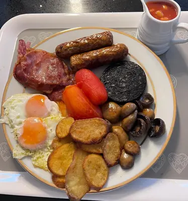 a plate of breakfast food with eggs sausage and vegetables at Falconwood in Ifton Heath