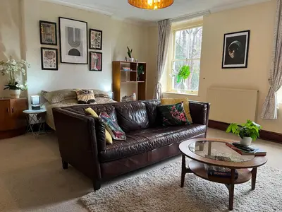 a living room with a brown leather couch and a table at Large Corris apartment with kitchen & lounge and adjoining bathroom in Dolgellau