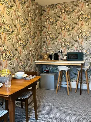 a dining room with a table and two stools at Large Corris apartment with kitchen & lounge and adjoining bathroom in Dolgellau