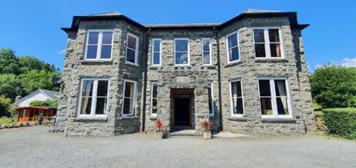 a stone house with a front door and windows at Large Corris apartment with kitchen & lounge and adjoining bathroom in Dolgellau