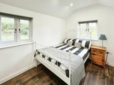 a bedroom with a white bed and two windows at Hên Stablau - Spacious Pet-Friendly Welsh Retreat by PolkaStays in Llanfihangel-Glyn-Myfyr