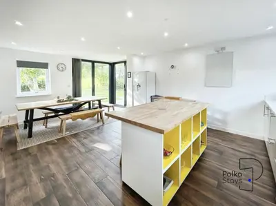 a kitchen with a table and a yellow and white island at Hên Stablau - Spacious Pet-Friendly Welsh Retreat by PolkaStays in Llanfihangel-Glyn-Myfyr