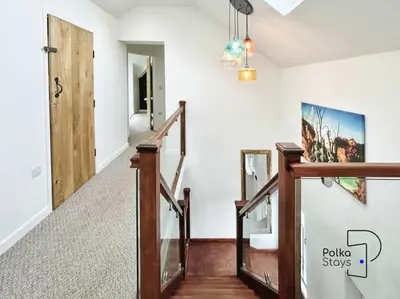 a staircase in a house with a painting on the wall at Hên Stablau - Spacious Pet-Friendly Welsh Retreat by PolkaStays in Llanfihangel-Glyn-Myfyr