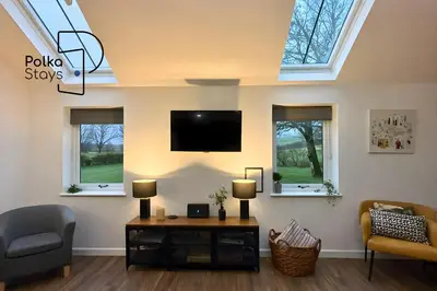 a living room with a tv and two windows at Hên Stablau - Spacious Pet-Friendly Welsh Retreat by PolkaStays in Llanfihangel-Glyn-Myfyr