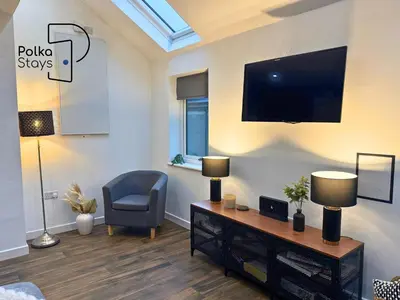 a living room with a tv and a chair at Hên Stablau - Spacious Pet-Friendly Welsh Retreat by PolkaStays in Llanfihangel-Glyn-Myfyr