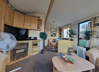 a caravan living room with a tv and a table at 2 Bed Caravan - Sleeps 4 - Pets - Parking - Wifi in Aberystwyth
