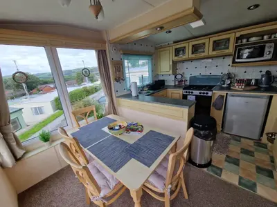 a kitchen with a table and chairs and a kitchen with a window at 2 Bed Caravan - Sleeps 6 - Pets - Pool - Parking in Aberystwyth