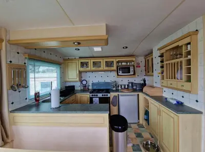 a small kitchen with wooden cabinets and counters at 2 Bed Caravan - Sleeps 6 - Pets - Pool - Parking in Aberystwyth