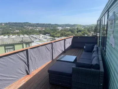 a balcony with a couch and chairs on a deck at 2 Bed Caravan - Sleeps 6 - Pets - Pool - Parking in Aberystwyth