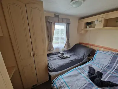 a small bedroom with two beds and a window at 2 Bed Caravan - Sleeps 6 - Pets - Pool - Parking in Aberystwyth