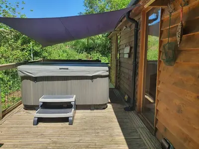 a patio with a tub and a bench on a deck at Swn Y Nant Lodge with hot tub Brecon in Brecon