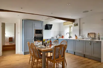 a kitchen with a table and chairs in a kitchen at Finest Retreats - Moelis Barn in Llandrillo