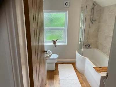 a bathroom with a toilet and a tub and a window at Little Hotspur in Shrewsbury