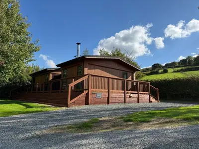 a large wooden cabin with a porch and a driveway at Charming 2 bedroom Lodge In the Shropshire Countryside with Fantastic Views in Clunton