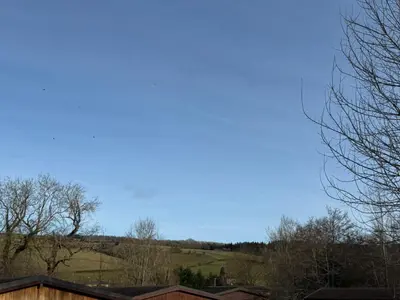 a blue sky over a hill with trees and houses at Charming 2 bedroom Lodge In the Shropshire Countryside with Fantastic Views in Clunton