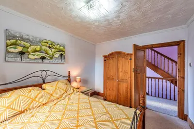 a bedroom with a bed and a staircase at Finest Retreats - Tan y Fron Hideaway in Dyffryn