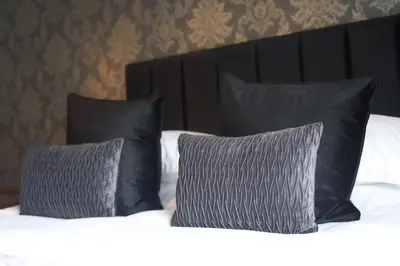 a bed with black pillows and white sheets at OYO Glyn Valley Hotel in Glyn-Ceiriog