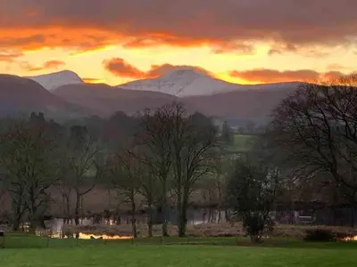 a sunset over a field with mountains in the background at Old Chapel Llanfrynach in Brecon