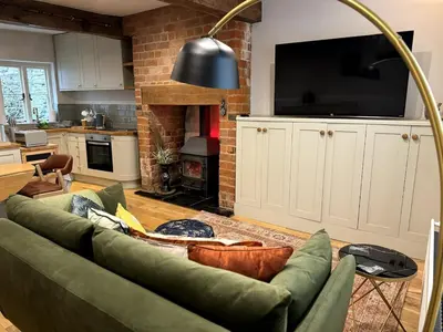 a living room with a green couch and a fireplace at The Cottage, Upper Linney, Ludlow in Ludlow