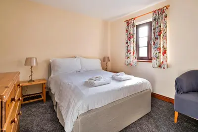 a bedroom with a bed and a chair and a window at Finest Retreats - Walton Maisonette in Onibury