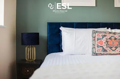 a bed with a blue headboard and white pillows at 4 bedroom house in Shrewsbury with parking in Shrewsbury