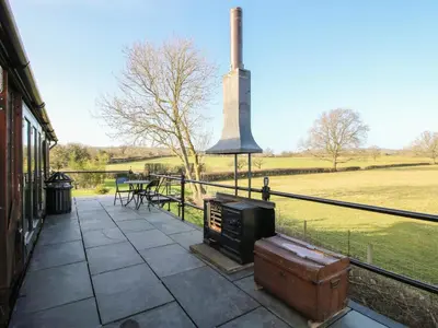 a outdoor patio with a stove and a field at GWR Wagon - Victoria Station in Craven Arms