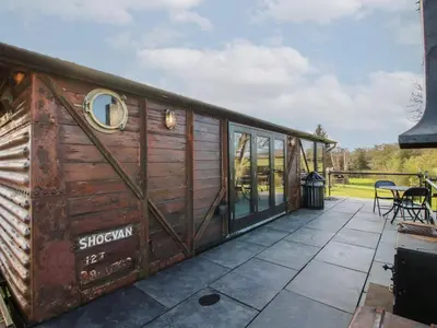 a wooden shipping container house with a patio at GWR Wagon - Victoria Station in Craven Arms
