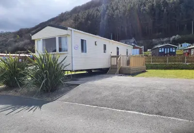 a small white trailer parked in a parking lot at Pet Friendly 3 Bed Static Caravan in Clarach Bay Spacious and Cozy Stay in Aberystwyth