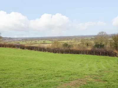 a field with a fence in the distance at Meadow View - Bryn-Mawr Retreat in Llanymynech