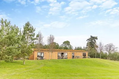 a wooden house on a hill with a green field at 4 Bed in Llansanffraid oc-p30384 in Llanymynech