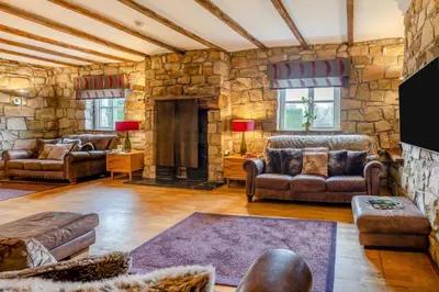 a living room with leather furniture and a stone wall at 14 Bed in Llansanffraid oc-b30382 in Llanymynech