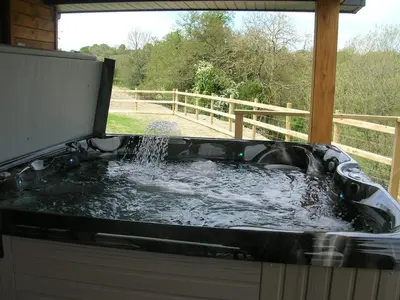 a bath tub filled with water in a yard at River Lodge Hot Tub Sleeps 6 in Hundred House