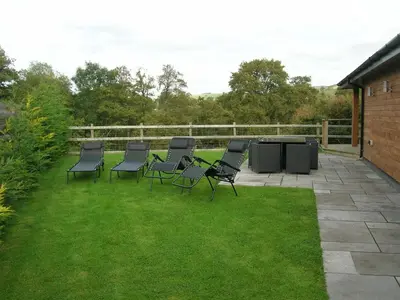 a group of chairs and a table on a lawn at Woodland Lodge Hot Tub Sleeps 6 in Hundred House